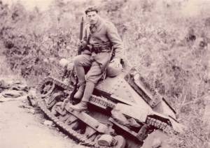 A Greek soldier sitting on a broken down Italian tank.